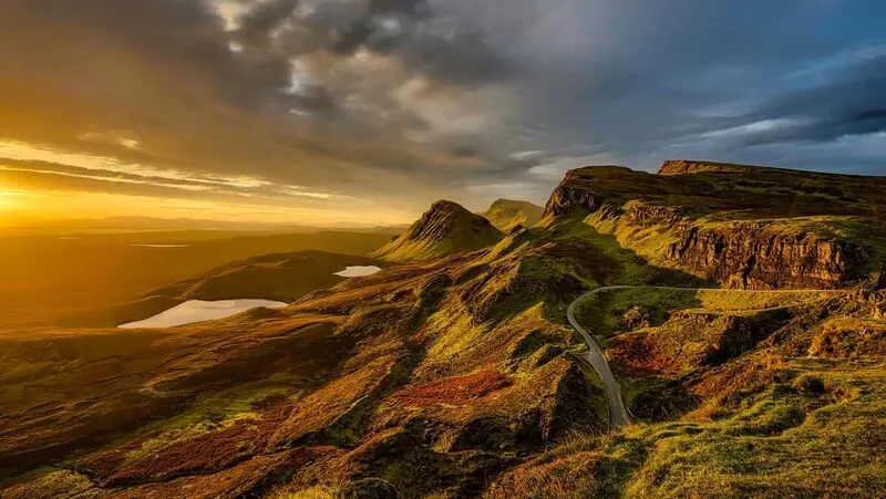 Image of mountains with a road winding up and a sunset in the background